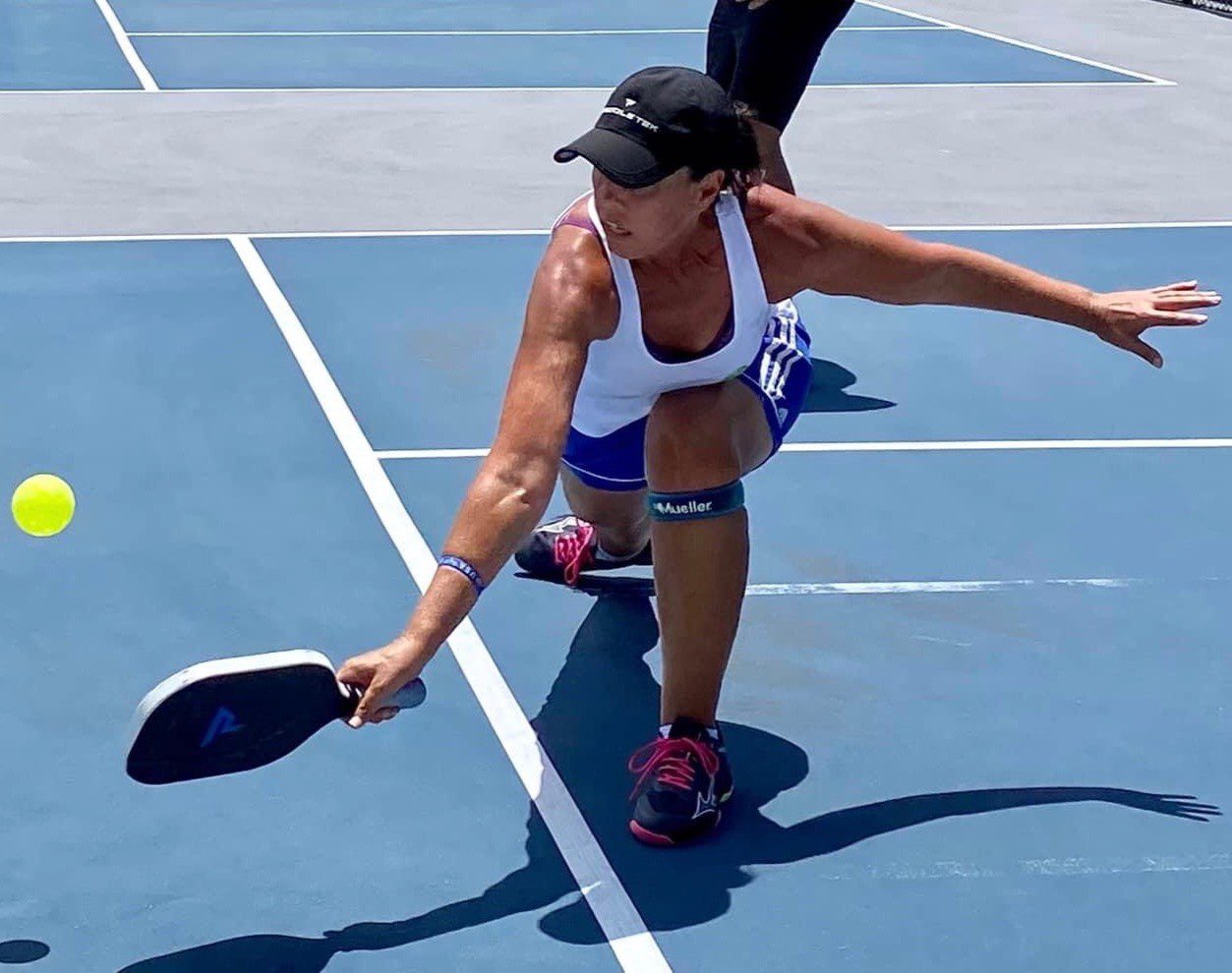 Player diving for a pickleball on court.